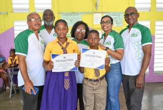 Members of the Morant Bay High School Alumni Association (MBHSAA) and Principal of Easington Primary School, Marigold Webber-Smith (centre), share a photo opportunity with the Top Girl and Top Boy, Jaysianna Hutchinson (third left) and Javien Robb (right), respectively,  at a ‘Community Give Back Day’ held at the institution in St. Thomas on Monday (October 12), as part of the MBHSAA’s Alumni Week activities.
