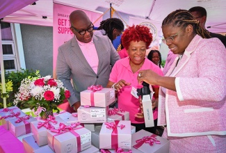 President of the Rotary Club of Downtown Kingston, Derrick Bernard, looks on as President of Jamaica Reach to Recovery, Sandra Samuels (centre), and Founder and Managing Director of Precision Imaging Centre, Dr. Derria Cornwall-Bernard, unbox a mastectomy bra. The occasion was a donation of breast prostheses and specialised mastectomy bras by the club and Precision Imaging Centre to benefit women who have undergone mastectomies. The handover took place on Wednesday (October 21) at the Jamaica Cancer Society (JCS) in Kingston and will be distributed through the non-profit organisation's breast cancer support arm, Jamaica Reach to Recovery programme.
