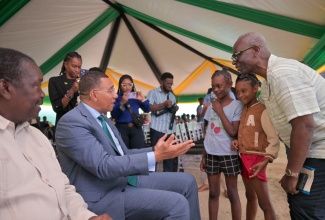 Prime Minister, Dr. the Most Hon. Andrew Holness (second left), greets young Tivoli Gardens residents Cathalia Collins (centre) and Mourica Rose, during the Certificate of Possession Handover Ceremony held at the Tivoli Gardens Community Centre in Western Kingston on Wednesday (October 14). Looking on are Minister without Portfolio in the Ministry of Economic Growth and Infrastructure Development with responsibility for Land Titling and Settlements, Hon. Robert Montague (left), and Minister of Local Government and Community Development and Member of Parliament for Western Kingston, Hon. Desmond McKenzie (right). Approximately 221 Tivoli Gardens residents received Certificates of Possession, bringing them one step closer to full homeownership.
