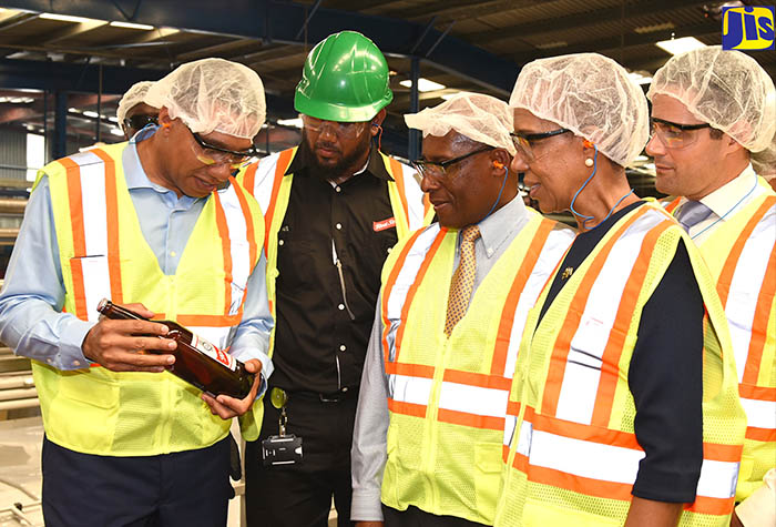 Prime Minister, the Most Hon. Andrew Holness (left), examines a Red Stripe bottle while on a tour of the brewery’s new production line, dubbed ‘Line 8’, and liquefied natural gas (LNG) plant, at the company’s Spanish Town Road facility on December 19.  Others (from second left) are Line 8 Project Manager, André Bennett; Executive Director of the National Growth Council, Aubyn Hill; State Minister in the Finance and the Public Service Ministry, Hon. Fayval Williams; and Vice President of Project Development, New Fortress Energy, Sam Abdalla. 