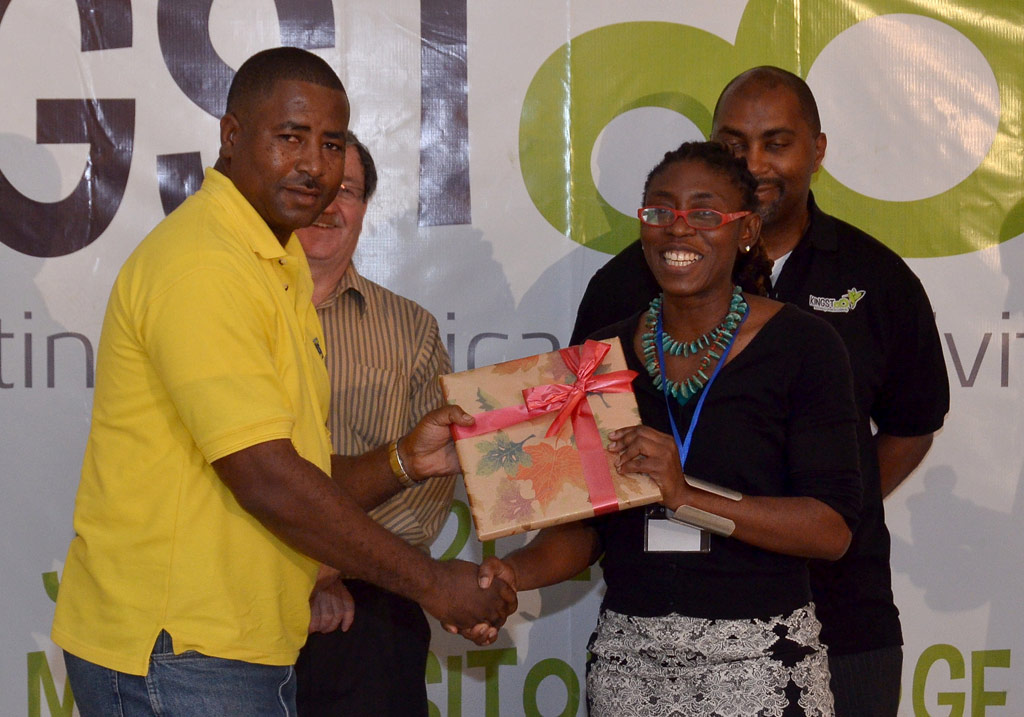 Photography Supervisor at the Jamaica Information Service (JIS), Dave Reid (left), accepts a token from Jamaica Promotions Corporation (JAMPRO) Creative Industries Manager and Film Commissioner, Kim Marie Spence, during the closing ceremony of the KingstOOn animation conference and film festival held on June 22 at the Mona Visitors’ Lodge, University of the West Indies (UWI). In background (right) is Minister of State in the Ministry of Science, Technology, Energy and Mining, Hon. Julian Robinson. KingstOOn was organised by the Government in partnership with the World Bank, the Canadian High Commission, and JAMPRO.