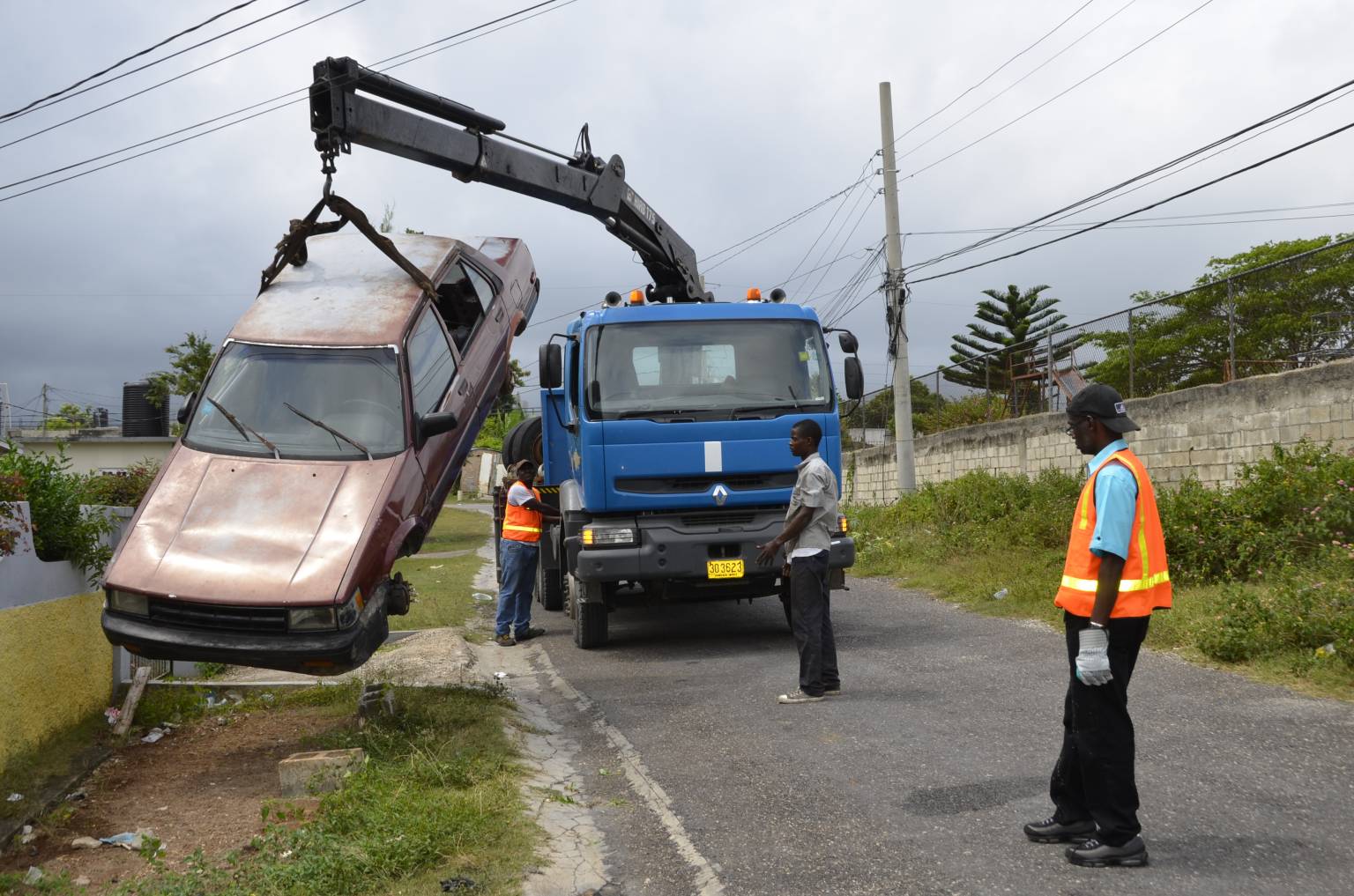 Permanent Secretary in the Ministry of Local Government and Community Development, Denzil Thorpe (right) watches as an old derelict car is removed by a crane in the Farm Heights community of St. James on Saturday, April 23. The removal, formed part of a clean-up project which was spearheaded by Local Government and Community Development Minister, Hon. Desmond McKenzie.