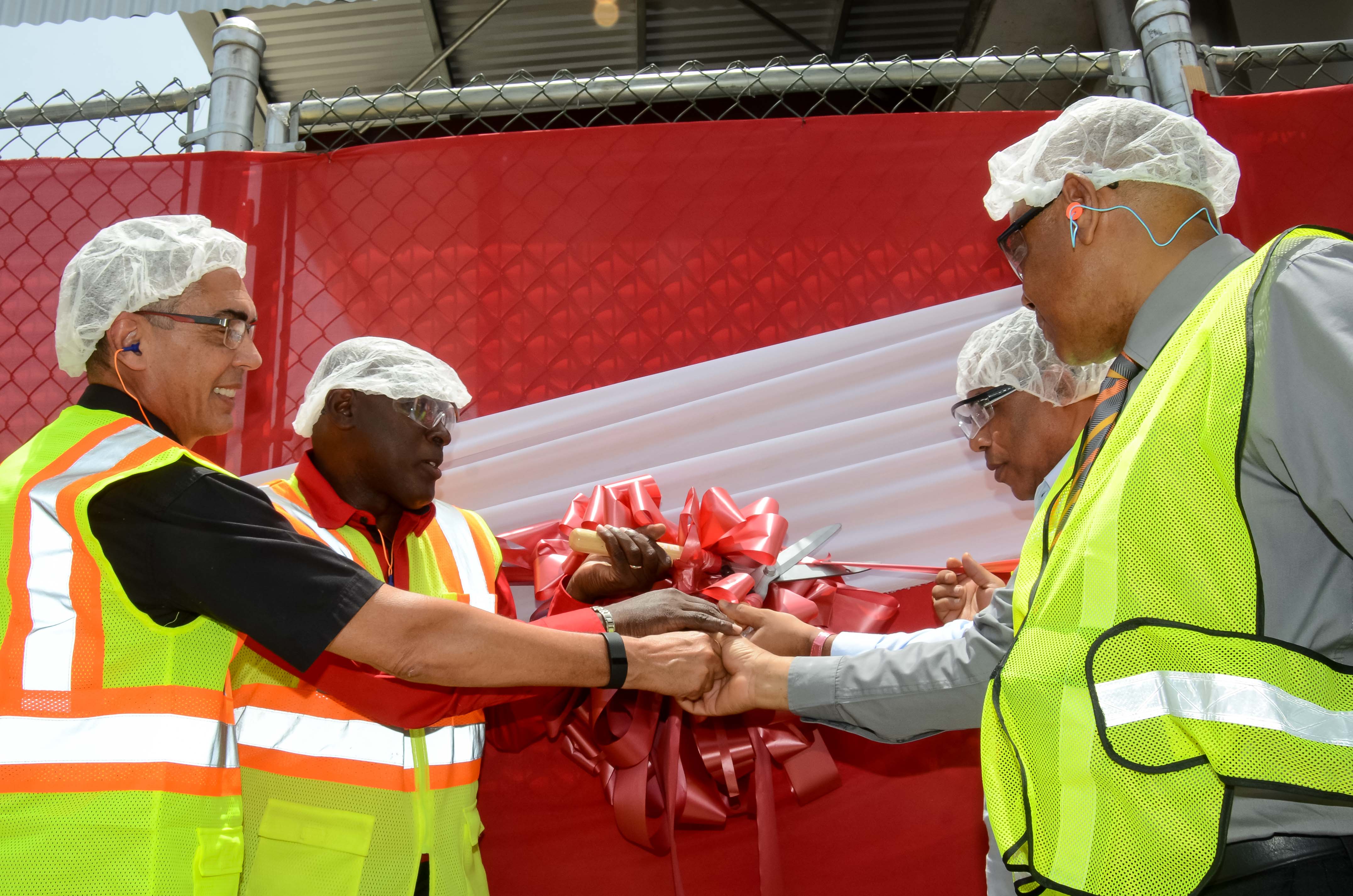 Minister of Agriculture, Labour and Social Security, Hon Derrick Kellier (right); and Minister of Industry, Investment and Commerce, Hon. Anthony Hylton (second right), join in cutting the ribbon to signify the official commissioning into service of brewery company, Red Stripe’s cassava starch factory, at its Spanish Town Road headquarters in St. Andrew, on June 18. Others taking part are (from left): Chairman, Richard Byles; and Managing Director, Cedric Blair.