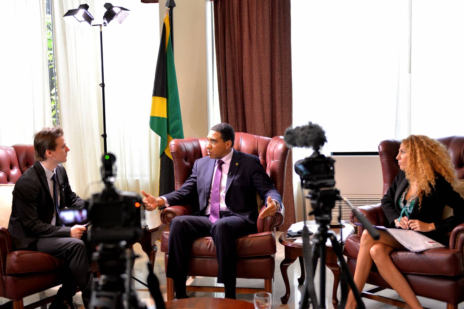 Prime Minister, the Most Hon. Andrew Holness (centre), responds to a question posed by Editor-in-Chief for World INvestment NEws (WINNE), Stan Aron (left), during an interview conducted at the Office of the Prime Minister (OPM) on Wednesday, April 13. Also pictured is Regional Market and Client Director for WINNE, Stéphanie Huertas.