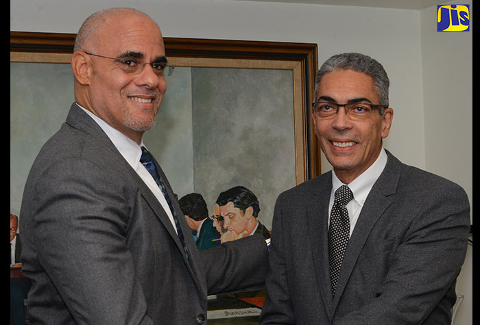 Co-Chair of the Economic Programme Oversight Committee (EPOC), Keith Duncan, shakes hands with former EPOC Co-Chair, Richard Byles, at a formal handover ceremony at the Sagicor Life Building in New Kingston today.