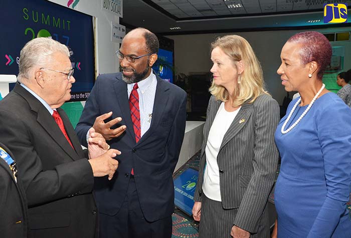 Industry, Commerce, Agriculture and Fisheries Minister, Hon. Karl Samuda (left), speaks with  General Manager of the Jamaica National Building Society (JNBS),  Earl  Jarrett (second left), at the second staging of the Social Enterprise Boost Initiative (SEBI) Summit 2017, organised by the JNBS Foundation, at The Jamaica Pegasus hotel in New Kingston, on January 30.  Others (from third left) are: Mission Director of the United States Agency for International Development (USAID), Maura Barry-Doyle; and State Minister in the Finance and the Public Service Ministry, Hon. Fayval Williams.