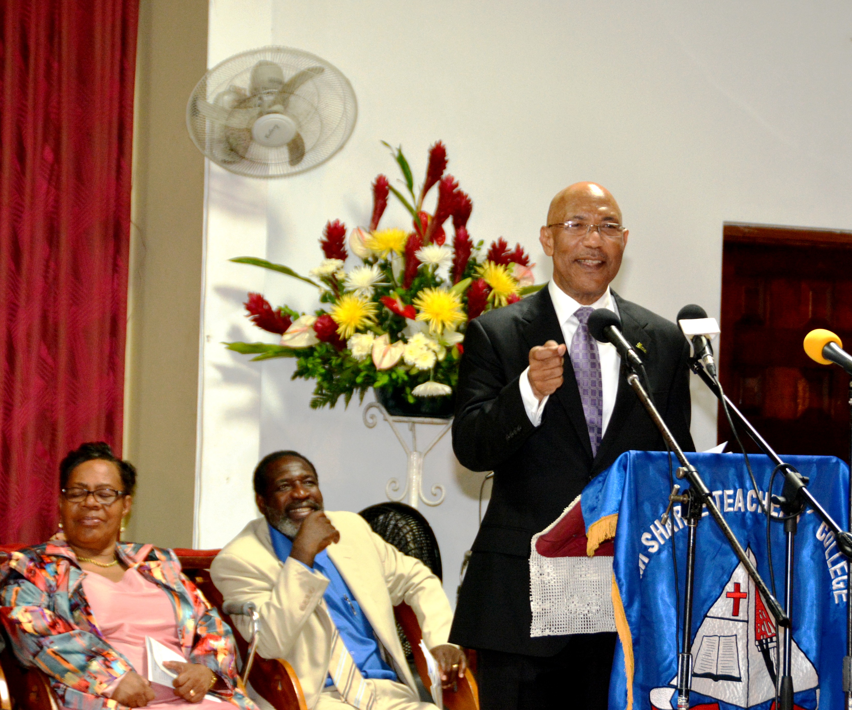 : Governor-General, His Excellency the Most  Hon. Sir Patrick Allen (right), addressing graduates of  Sam Sharpe Teachers’ College  at their Valedictory Service,  held at Calvary Baptist Church in Montego Bay, on  May 28. Also on the platform are (from left), past principal, Dr. Cecile Walden and Master of Ceremony, Rev. Godfrey Francis.