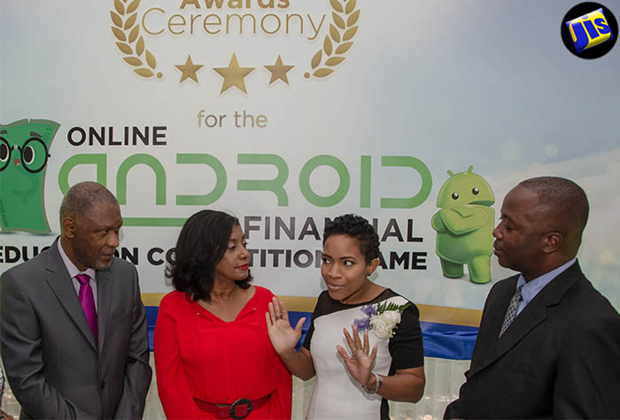 Chairman of the Jamaica Deposit Insurance Corporation (JDIC), John Jackson (left); Chief Executive Officer of the JDIC, Antoinette McKain (second left) and Senior Education Officer at the Ministry of Education, Youth and Information, Marlon Williams (right), listen intently to Founder of AIM Educational Services, Nicole McLaren Campbell, at the JDIC awards ceremony, held on July 1 at the Terra Nova All-Suite Hotel in Kingston.