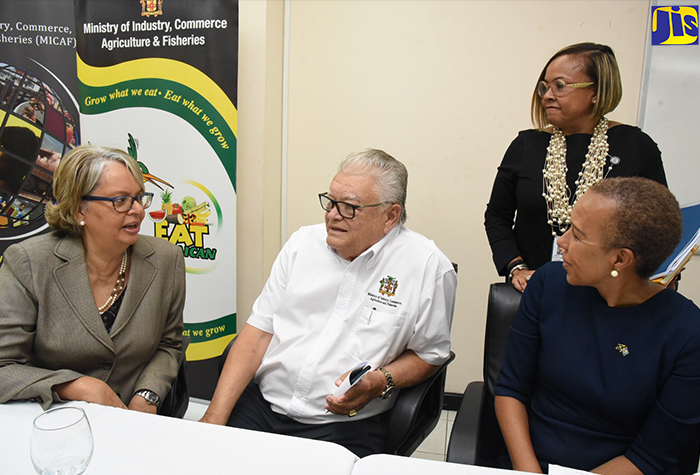 Minister of Industry, Commerce, Agriculture and Fisheries, Hon. Karl Samuda (seated, centre) in discussion with (from left), Chairperson, Trade Facilitation Task Force, Patricia Francis, and State Minister for Finance and the Public Service, Hon. Fayval Williams. Occasion was a signing ceremony for an advisory agreement with International Finance Corporation (IFC) for the establishment of a national trade portal. The event was held at the Ministry’s St. Lucia Avenue location in New Kingston on December  19.  Standing is Head of Operations, IFC, Judith Green. 