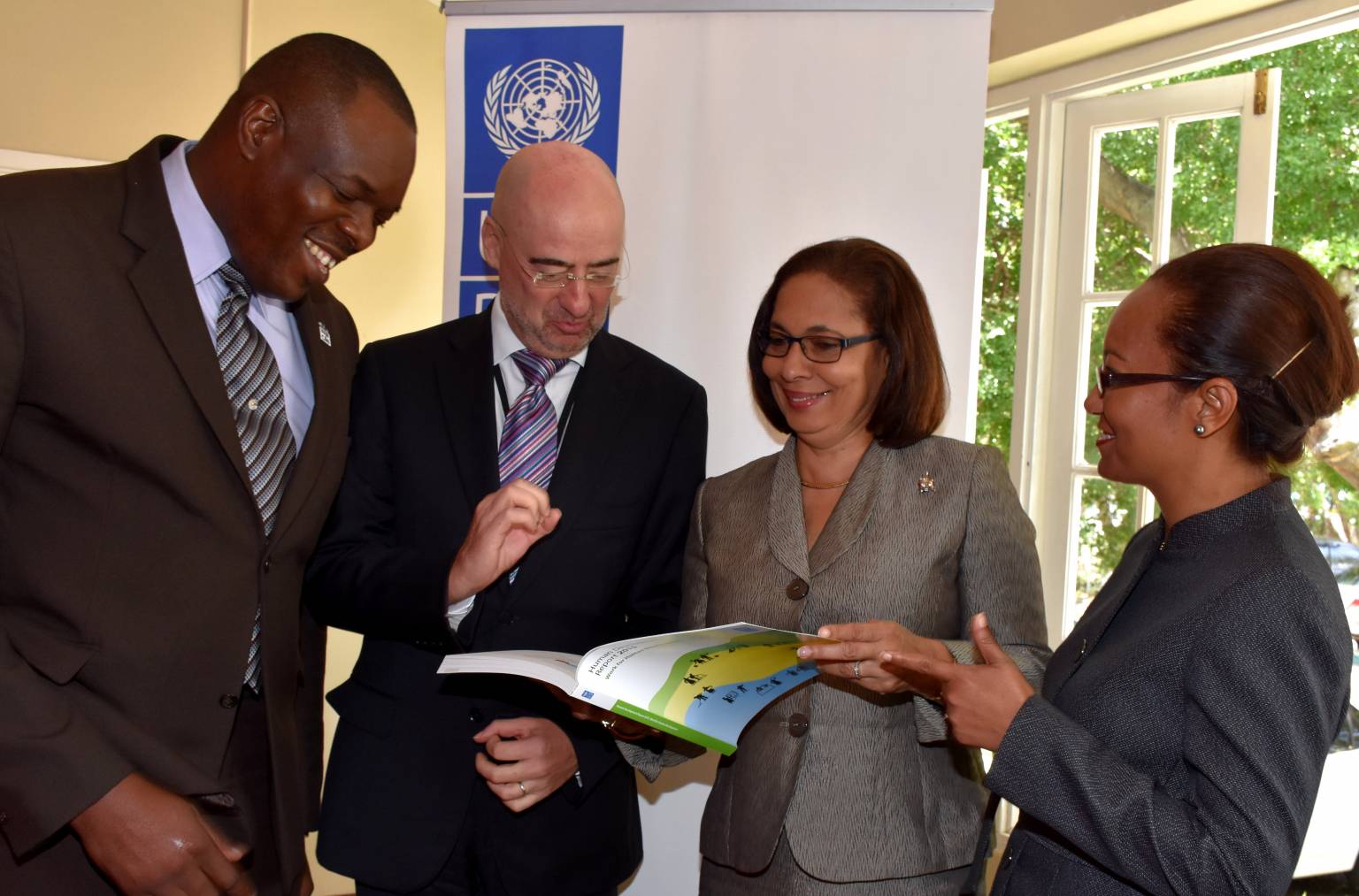 Labour and Social Security Minister, Hon. Shahine Robinson (2nd right), peruses the United Nations Development Programme’s (UNDP) 2015 Human Development Report on Work with UNDP Resident Representative, Bruno Pouezat (2nd left). The occasion was a Workers Week panel discussion at the Liguanea Club in New Kingston on May 18. Others (from left) are: Executive Director of the HEART Trust/NTA, Dr. Wayne Wesley (left); and Permanent Secretary in the Ministry, Colette Roberts Risden. 