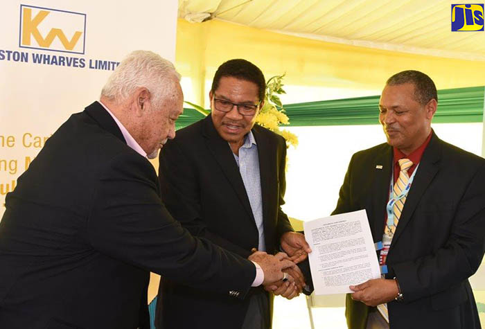 Minister of Transport and Mining, Hon. Mike Henry (left), congratulates Chief Executive Officer of Kingston Wharves Limited (KWL), Grantley Stephenson (centre), after signing and handing over the lease arrangements for the KWL’s Global Auto Logistics Centre. Sharing the moment is President and Chief Executive Officer of the Airports Authority, Audley Deidrick. Occasion was the launch of the facility located at Tinson Pen in St. Andrew on Friday (December 15).