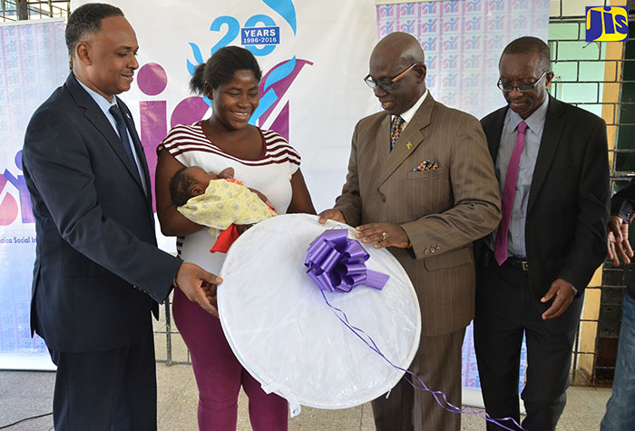 Local Government and Community Development Minister and Member of Parliament for West Kingston, Hon. Desmond McKenzie (2nd right); and Managing Director of the Jamaica Social Investment Fund (JSIF), Omar Sweeney (left), hand over a mosquito net to Tivoli Gardens resident, Tara Clarke (2nd left), who is holding her newborn. Sharing the moment is Director of the Environmental Health Services in the Ministry of Health, Everton Baker. Several residents of West Kingston were presented with mosquito nets and water container covers during a ceremony held on April 11 at Tivoli Gardens Community Centre in Kingston. 