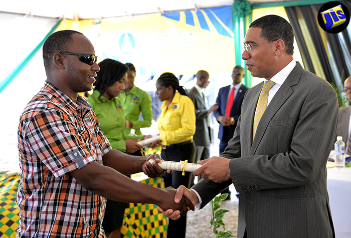 Prime Minister, the Most Hon. Andrew Holness (right), hands over a land title to Donald Miller, one of over 220 recipients of land titles at a ceremony held by the Land Administration and Management Programme (LAMP), at Jamaica House, on  August 23. Mr. Holness gave the keynote address at the ceremony.