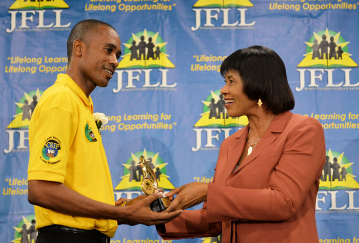 Prime Minister Portia Simpson Miller presents Mr. Leroy Gooden with the trophy for most outstanding male student at the Majesty Gardens Community Education Programme Graduation Ceremony held at the Knutsford Court Hotel on Wednesday, July 8.  Mr. Gooden was among seventy-seven graduates who received certificates of participation and competence. The programme was spearheaded by the Jamaica Foundation for Lifelong Learning, The Planning Institute of Jamaica (through its Community Renewal Programme) and the Citizens Security and Justice Programme (CSJP) which operates out of the Ministry of Justice. 