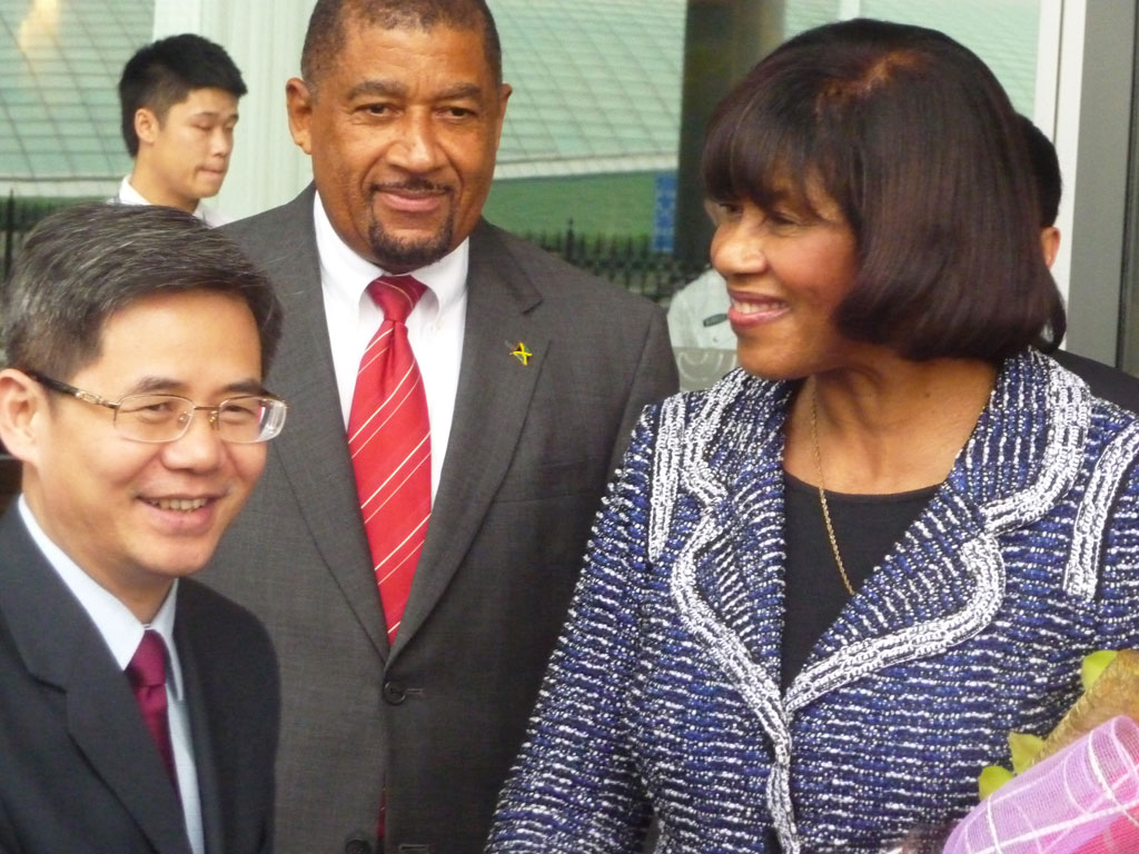 Prime Minister the Most Hon. Portia Simpson Miller (right), is greeted by Assistant Foreign Minister, People’s Republic of China, Zheng Zeguang (left); and Jamaica