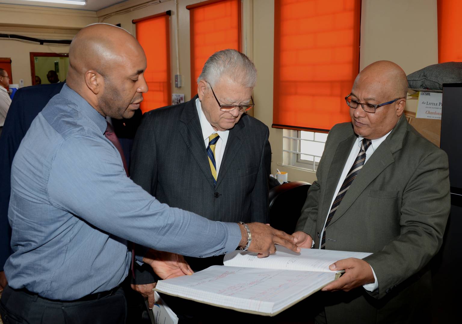 Industry, Commerce, Agriculture and Fisheries Minister, Hon. Karl Samuda (centre), peruses a Customs  log book being shown to him by the Chief Information Officer, Andre Williams (left) and Commissioner of Customs, Major Richard Reese, during a tour of several departments of the Jamaica Customs Agency, located at Newport East, in Kingston, on March 15.    