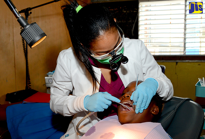 Student of the University of Technology (UTech) Dental programme, Chinel Lee, applying sealant to the teeth of grade-six Clan Carthy Primary School student, Joevielia Brown, at the launch of the Ministry of Health’s National Sealant Programme, held on March 21 at the School in Kingston. The programme aims to provide access to preventative oral and dental care for primary- and basic-school children.