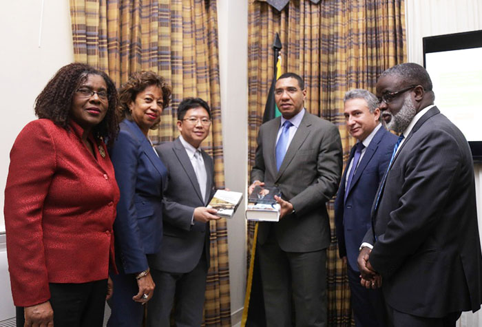 Prime Minister Andrew Holness is presented with books on the development of Singapore by Daniel Seah (third left), Deputy Director, Singapore Corporation Enterprise during a meeting at the Office of the Prime Minister today. Looking on are: (L-R) Mrs Audrey Sewell, Permanent Secretary, Office of the Prime Minister; Diana Edwards, President, Jampro; Metry Seaga, Chairman, Special Economic Zone and Dr Eric Deans, CEO, Special Economic Zone 