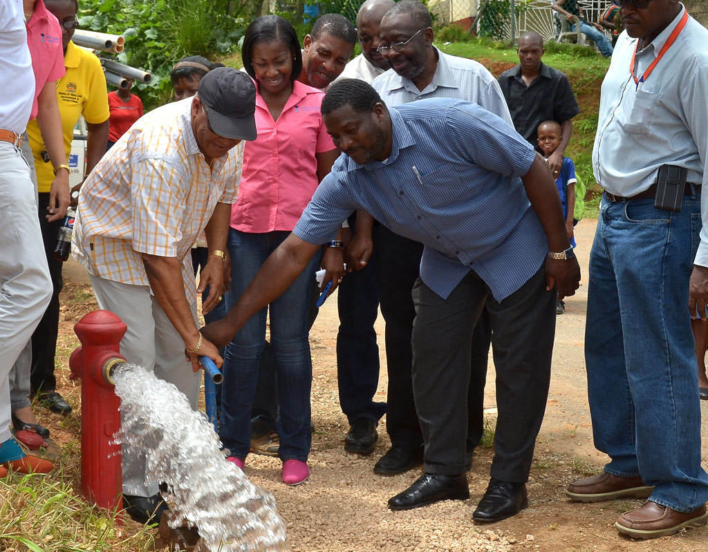 Water, Land, Environment, and Climate Change Minister, Hon. Robert Pickersgill (left), is assisted by Councillor for the Treadways Division in St. Catherine, Sydney Rose (2nd right), to turn on phase two of the John Groyne water supply system, during Friday’s (June 21) commissioning ceremony. Sharing the occasion are staff members of Rural Water Supply Limited (RWSL), which undertook the $13 million development, the National Water Commission (NWC), which will be responsible for its maintenance, and residents of the community.