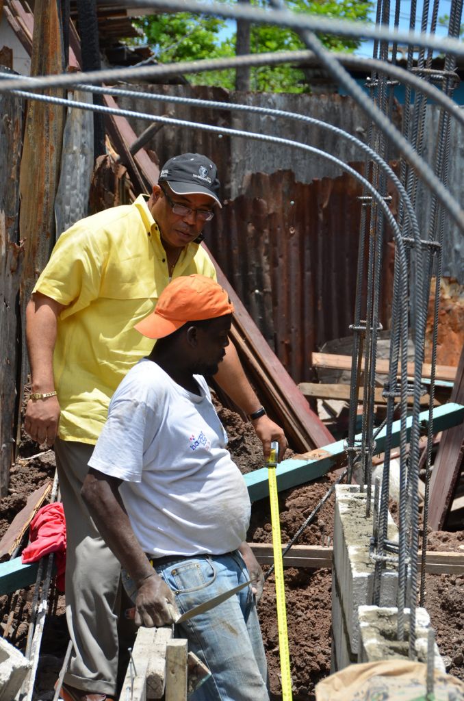 Minister of Industry, Investment and Commerce, and Member of Parliament for St. Andrew Western, Hon Anthony Hylton, assists mason, Odelie Wright, as they participate in the re-building of the home of an elderly resident of the Waterhouse community, during Labour Day activity today (May 23). 
