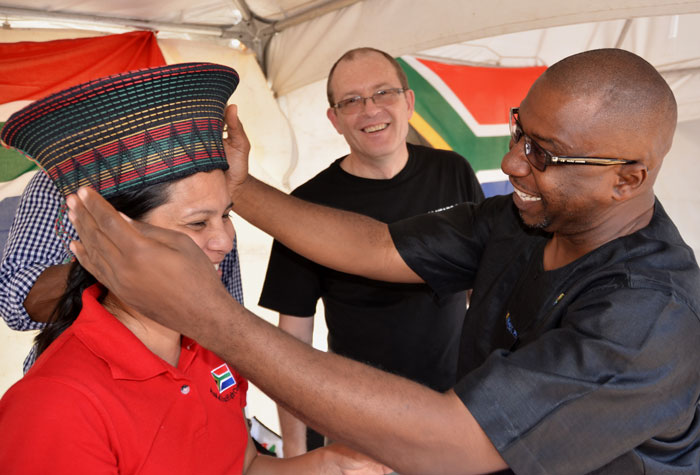 Deputy Mayor of Kingston, Andrew Swaby (right), fits a hat on the head of Social Secretary at the South African High Commission, Carleen Lowe,  at the African Liberation  Day celebration, hosted by the Kingston and St. Andrew Corporation (KSAC), at the St. William Grant Park in Downtown Kingston, on May 24.  Looking on is Phillip Riley of the South African High Commission.