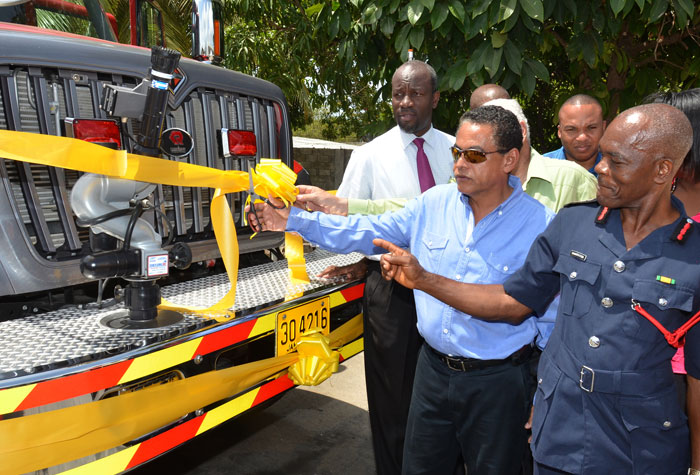 Minister of Local Government and Community Development, Hon. Noel Arscott (centre), cuts ribbon  to officially  hand over new fire truck to Clarendon at the May Pen fire station on July 24. Others  (from left): Mayor of May Pen, Councillor Scean Barnswell (left); Member of Parliament for Central Clarendon, Mr. Mike Henry, and Assistant Commissioner of the Jamaica Fire Brigade, John Forester.