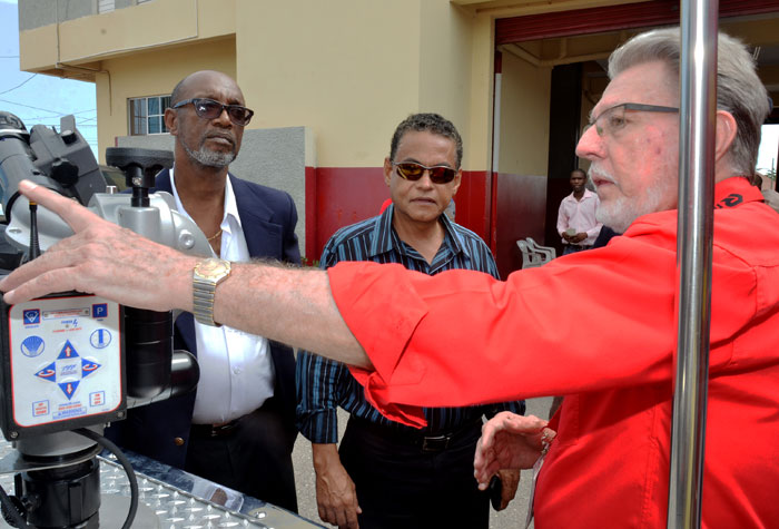 Minster of Local Government and Community Development, Hon. Noel Arscott (centre), and State Minister, Hon. Colin Fagan (left), look on as Chief Executive Officer and Director of National Safety Limited, Julian Templer, demonstrates the use of a device on one of three new fire trucks provided to the Jamaica Fire Brigade. The trucks were handed over at the Portmore Fire Station in St. Catherine last Friday (July 18).