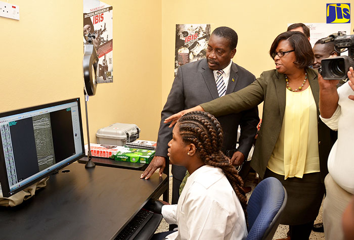 Minister of National Security, Hon. Robert Montague (left), listens as Executive Director, Institute of Forensic Science and Legal Medicine, Dr. Judith Mowatt (second left), explains features of the BULLETRAX-3D System. Seated is Firearms and Toolmarks Examiner at the Institute, Stephanie Blake. The system has been donated by the United Nations Regional Centre for Peace, Disarmament and Development in Latin America and the Caribbean.