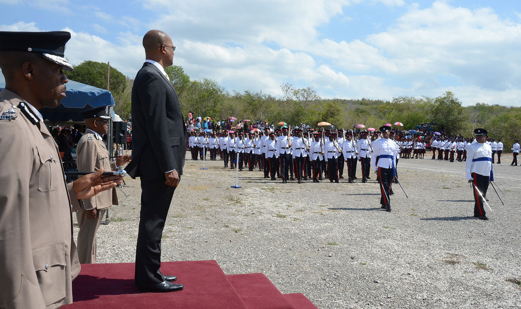 Minister of National Security, Hon. Peter Bunting (on dais), observes as new police recruits go through their paces, at the passing out parade and award ceremony at the National Police College of Jamaica in Twickenham Park, St. Catherine on August 14. He is flanked by Police Commissioner,  Dr. Carl Williams (left); and Deputy Commissioner, Delworth Heath.