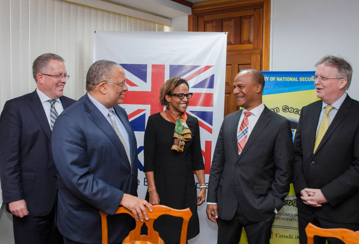 Minister of Finance and Planning, Dr. the Hon. Peter Phillips (2nd left), having a light exchange with Minister of National Security, Hon. Peter Bunting (2nd right), at a contract signing ceremony  for Phase Three of the Citizen Security and Justice Programme (CSJP) on December 11 at the Ministry of Finance and Planning, in Kingston.   Others (from left) are: Canadian High Commissioner, Robert Ready; Country Representative of the Inter-American Development Bank, Therese Turner-Jones and British High Commissioner, David Fitton.