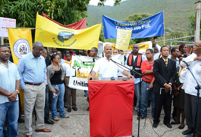 National Security Minister, Hon. Peter Bunting (at podium), addresses residents of Rockfort in East Kingston, and other stakeholders participating in Sunday’s (February 16) walk through, which culminated along Oliver Road in the community. The walk was a show of support for peace efforts being pursued, in the wake of recent gang violence in the area resulting death and injury of several persons. Also participating were: Science, Technology, Energy and Mining Minister and Member of Parliament for the Area, Hon. Phillip Paulwell (left); and  Police Commissioner, Owen Ellington (2nd left).