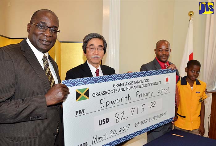 Minister of Education, Youth and Information (left), Senator the Hon. Ruel Reid (left); Japan’s Ambassador to Jamaica, His Excellency Masanori Nakano (second left); Principal, Epworth Primary School, Kirk Spencer;  and student, Epworth Primary School, Samuel Henry, display a symbolic cheque during a signing ceremony at the Ambassador’s Paddington Terrace residence in St. Andrew on March 30. The $10 million (US$82,715) to the institution will be used to construct two additional classrooms.   The money has been provided under the Japanese Government’s Grant Assistance for Grassroots Human Security Projects and initiated through a partnership forged between the National Education Trust (NET) and the Japanese Embassy in Jamaica.