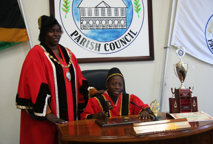 New Youth Mayor for Hanover,  11-year old Clinton Brown (right), is about to strike the gavel to convene his first meeting under the guidance of Mayor of Lucea, Councillor Shernet Haughton (left).  This follows his selection and installation on Monday (November 18), during a ceremony held at the Parish Council chambers in Lucea.