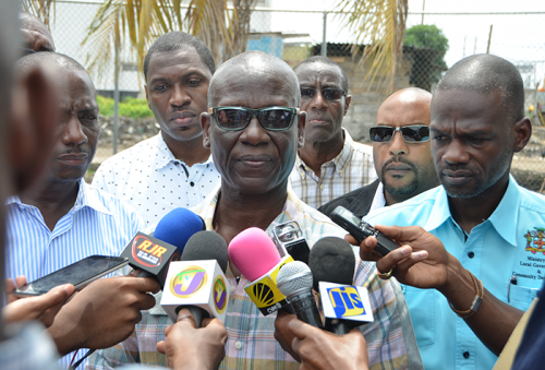 Local Government and Community Development Minister, Hon. Desmond McKenzie (centre), addresses journalists following a tour of flood-affected sections of Marcus Garvey Drive in Kingston on September 16. Also pictured are: National Solid Waste Management Authority (NSWMA) Chief Technical Officer, Audley Gordon (left); Kingston and St. Andrew Corporation (KSAC) City Engineer, Norman Shand (3rd right); KSAC Town Clerk, Robert Hill (2nd right); and Permanent Secretary, Ministry of Local Government and Community Development, Denzil Thorpe.