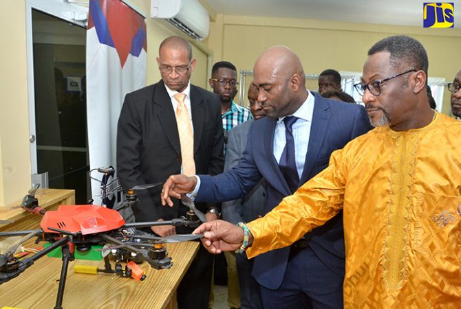 Minister of Science, Energy and Technology, Dr. the Hon. Andrew Wheatley (second right), examines his new drone which was made in the Dr Andrew Wheatley Centre for Digital Innovation & Advanced Manufacturing and presented to him as a gift on Wednesday, November 15. Occasion was the official opening of the facility. At right is the Chancellor, Caribbean Maritime University, His Royal Majesty Drolor Bosso Adamtey I.