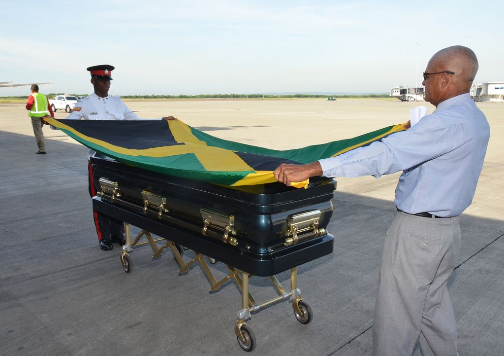 Members of the Jamaica Constabulary Force (JCF) drape the coffin of former Mayor of Portmore, George Lee, with the Jamaican flag, when the body arrived at the Norman Manley International Airport, in Kingston, today (October 14). Mr. Lee, who died on September 29 in Florida after a period of illness, is to be accorded an official funeral by the Government of Jamaica. The funeral service will take place at The Power of Faith Ministries, Portmore, on Thursday, October 17, beginning at 11:00 a.m.