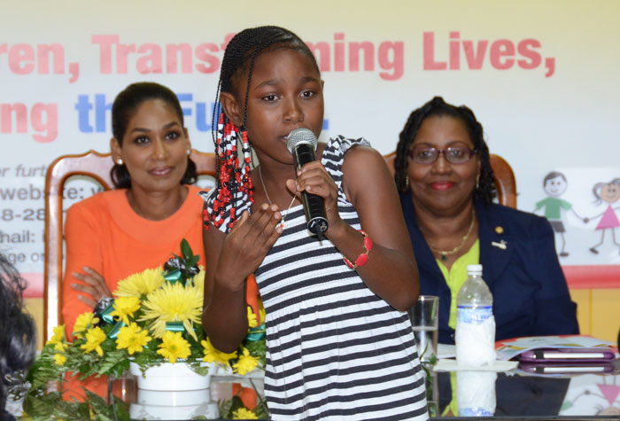 Minister of Youth and Culture, Hon. Lisa Hanna (left, background) and Director and Chairperson of the Child Development Agency’s (CDA)10th anniversary Committee, Michelle McIntosh, listen as Monisha Farquharson performs a cultural item during the media launch of the agency’s anniversary celebrations at its downtown Kingston offices, on May 28. The year-long activities to commemorate the CDA’s 10th anniversary begin on June 1 at the Boulevard Open Bible Church. Other activities include: lecture series, walk/runathon, awards banquet, concert, and talent competition exposition, among others.