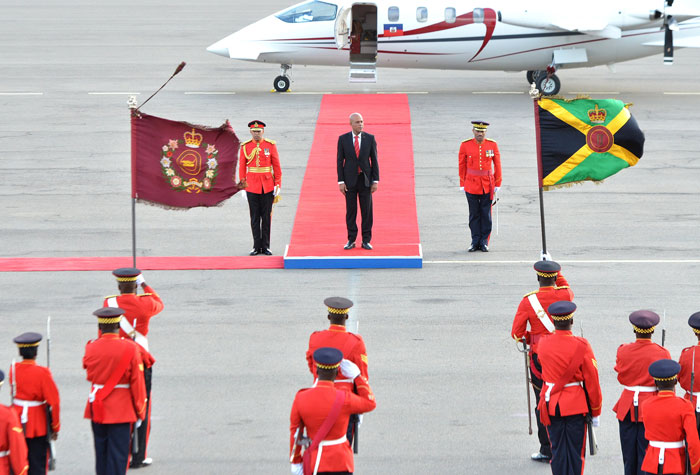 President of Haiti, His Excellency Michel Martelly (centre), is flanked by members of the Jamaica Defence Force (JDF), as he stands at the saluting dais for the playing of the National Anthem on his arrival at the Norman Manley International Airport on Wednesday (November 13) for a three-day State Visit.