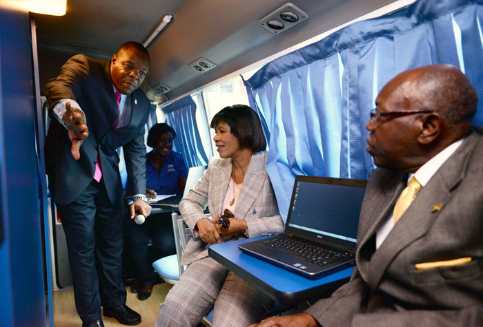 Prime Minister, the Most Hon. Portia Simpson Miller (2nd right), and Labour and Social Security Minister, Hon. Dr. Fenton Ferguson (right), observe as HEART Trust/NTA Executive Director, Dr. Wayne Wesley (left), explains aspects of the agency’s new mobile services programme, during the initiative’s recent launch at the St. Thomas Technical High School in Eastern St. Thomas.  Also observing is HEART’s Client Service Representative, Mervis Laing. 