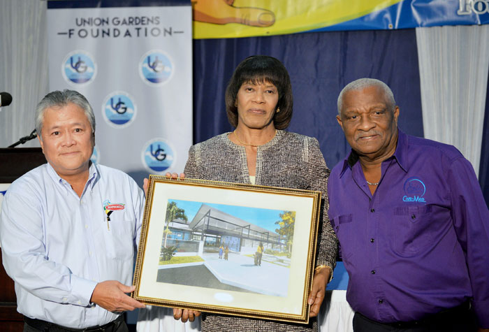 Prime Minister, the Most Hon. Portia Simpson Miller (centre), is presented with a copy of the architectural design for the proposed Union Gardens Infant School, by Director of the Union Gardens Foundation (UGF), Gary Hendrickson (left), while Chairman of CARI-MED and UGF, Glen Christian (right), shares the moment. Occasion was the launch of the project on March 4, at the Jamaica Pegasus Hotel in New Kingston. The project will benefit some 150 students in the South West St. Andrew community. 