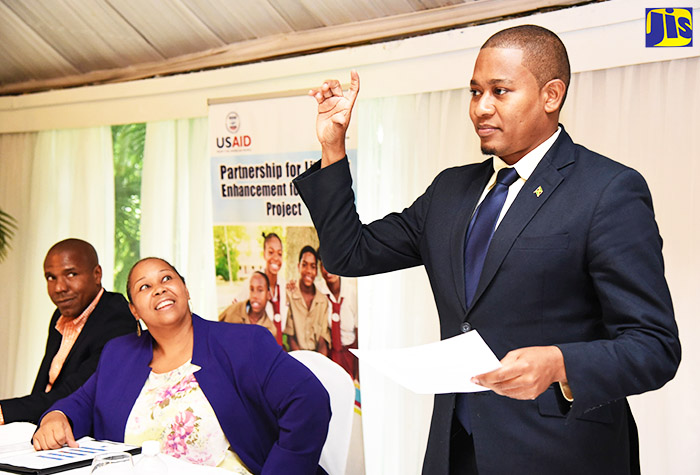 State Minister for Education, Youth and Information, the Hon. Floyd Green (right), spells his name in sign language at the launch of the Partnership for Literacy Enhancement for the Deaf Project on Wednesday (September 13) at the Terra Nova All-Suite Hotel in Kingston. Looking on are Chairman of the Executive Board of the Jamaica Association for the Deaf (JAD), Christopher Williams; and Acting Mission Director for the United States Agency for International Development (USAID), Rebecca Robinson.