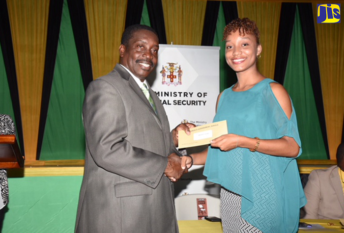 Minister of National Security, Hon. Robert Montague (left), presents Mikayla Crossdale with a scholarship valued at $200,000 during the Jamaica Police Federation/Ministry of National Security awards ceremony at the Girl Guides Association of Jamaica headquarters in Kingston on October 19. A total of 62 scholarships were presented to children of police officers, who are pursing tertiary studies.