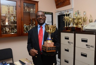 Principal of Windward Road Primary and Junior High School in Kingston, Norman Malcolm, displays the Carol Miller Trophy for the Most Avid (Student) Reader, one of the many trophies occupying his office. A miniature version of this award is presented to the student who reads exceptionally throughout the academic year. 