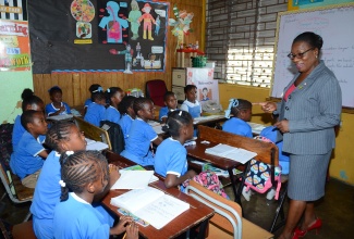 Principal, Alpha Primary School, Millicent Graham, engages with Grade 3 students. The South Camp Road-based institution is celebrating its 125th anniversary this year.