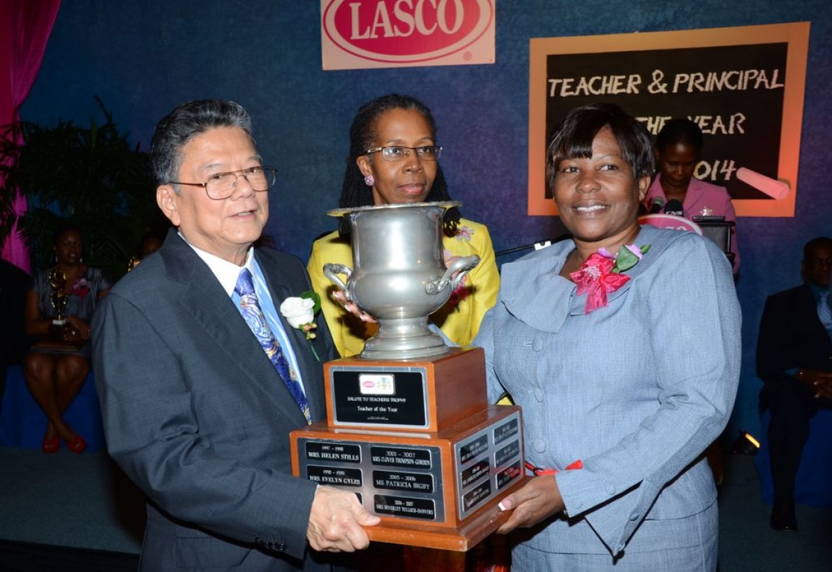 Founder and Executive Chairman LASCO Affiliated Companies, Lascelles Chin (left), presents the LASCO/Ministry of Education Teacher of the Year trophy to Janet Walters (right) from the John Rollins Success Primary School, St. James, during the recent awards ceremony held at the Jamaica Pegasus Hotel New Kingston. At centre is Permanent Secretary, Ministry of Education, Elaine Foster Allen. 