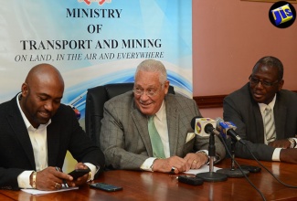 Transport and Mining Minister, Hon. Mike Henry (centre), consults with Science, Energy and Technology Minister, Dr. the Hon. Andrew Wheatley (left), during a media briefing at the Transport Ministry’s offices in St. Andrew, on July 28. At right is Permanent Secretary in the Mining Ministry, Dr. Alwin Hales.