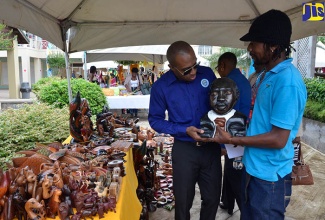 Executive Director of the Tourism Product Development Company (TPDCo), Dr. Andrew Spencer,  admires a bust of National Hero Marcus Garvey done by sculptor Dwight Thomas of Negril. Occasion was a tour at the Uniquely 876 Craft Fair, which was staged by the TPDCo at the Whitter Village in Ironshore, Montego Bay, on Thursday (December 14).   