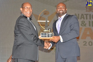 Minister of Science, Energy and Technology, Dr. the Hon. Andrew Wheatley (right), presents the National Medal for Science and Technology trophy to Dr. Henry Lowe, at the last Award ceremony held at The Jamaica Pegasus in November 2016.

