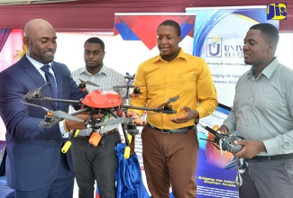 Minister of Science, Energy and Technology, Dr. the Hon. Andrew Wheatley (left), examines a drone that was made in the Andrew Wheatley Centre for Digital Innovation and Advanced Manufacturing. The drone was presented to him as a gift at the official opening of the Centre on Wednesday (November 15) at the Caribbean Maritime University (CMU) at Palisadoes Park, Kingston.

