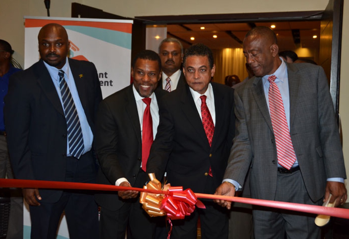 Minister of Local Government and Community Development, Hon. Noel Arscott (second right), is assisted by Mayor of Montego Bay, Councillor Glendon Harris (right) and Executive Director of the Caribbean Disaster Emergency Management Agency (CDEMA), Ronald Jackson (second left), to cut the ribbon to officially open the 8th Caribbean Conference on Comprehensive Disaster Management (CDM), at the Hilton Rose Hall Resort and Spa in Montego Bay, on December 2. The five-day conference is being held under the theme: 'CDM for resilient development: a good investment'. At left is Acting Director General of the Office of Disaster Preparedness and Emergency Management (ODPEM), Richard Thompson.  